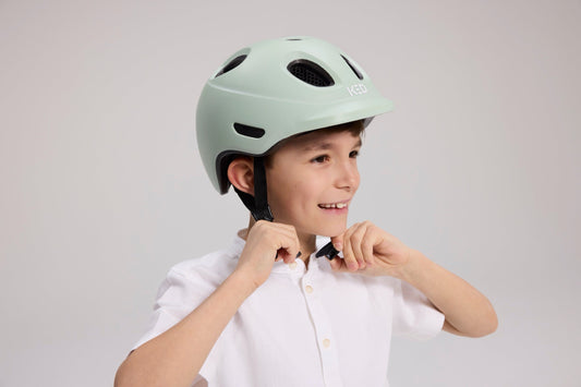 Junge schließt den Verschluss seines KED Fahrradhelms unter dem Kinn