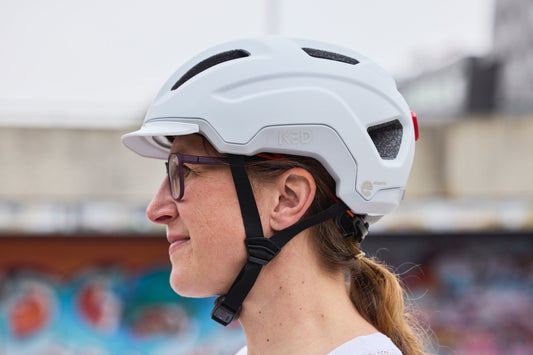 Radfahrerin im Seitenprofil mit weißem KED Pedalon Helm und Visier